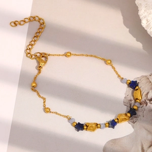 Detailaufnahme eines vergoldeten Armbands mit blauen Sternenperlen und Goldkugeln