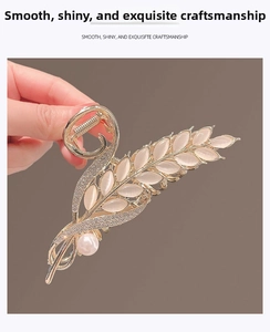 Macro shot of golden wheat hair claw with cat eye stone, rhinestones and pearl detail