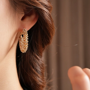 Close-up of gold pavé hoop earrings with shimmering crystals on model ear for elegant style