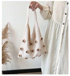 Detail of hand-crocheted cream knit tote bag with 3D brown floral accents and soft texture