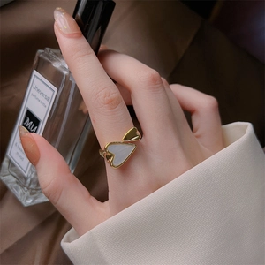 Minimalist 18K gold heart ring with white shell inlay shown on hand in elegant setting