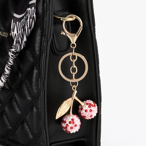 Porte-clés cerise en cristal rose étincelant sur un sac à main noir matelassé de luxe