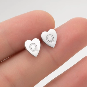Gros plan sur un clou d'oreille en acier inoxydable en forme de cœur avec lettre Q