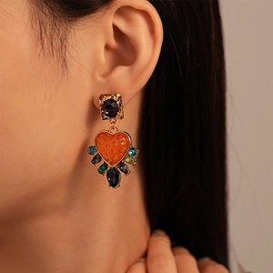 Vintage gold heart earrings with purple resin stone and colorful crystals worn by a model