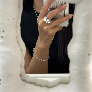 Close-up of a 925 sterling silver twisted chain bracelet and a beaded ring on a hand