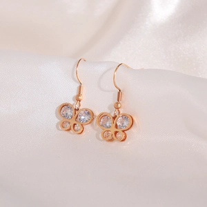 Close-up of rose gold butterfly earrings with clear zircons on white silk background