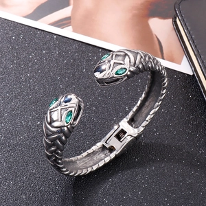 Detailed macro view of silver snake bangle featuring green gemstone eyes and scales
