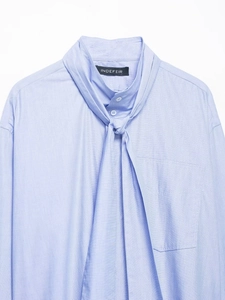 Close-up of pussy-bow tie neck and button detail on light blue long sleeve shirt