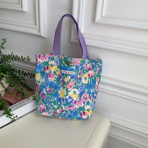 Dettaglio ravvicinato di una borsa tote in tela floreale con manici viola e motivi colorati