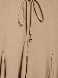 Detail of khaki chiffon dress waist featuring tie-up belt with gold metal charms
