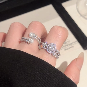 Close-up of elegant oval zircon ring and pearl cross ring on hand with shimmering pavé details
