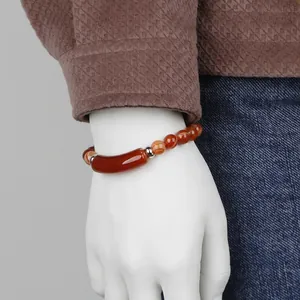 Red agate beaded bracelet with central curved tube bead and silver spacers on wrist