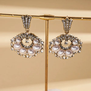 Detailed macro view of gold geometric drop earrings with pearls and crystal rhinestones