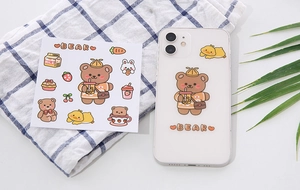 Detail view of cute cartoon bear PVC stickers applied on a smartphone case with milk motifs