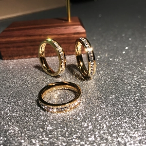 Dettaglio di anelli eternity dorati con pavé di zirconi su un supporto in legno