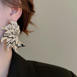 Detailed view of large silver metal earrings with radial pleats on an Asian model
