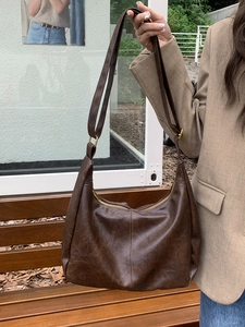 Detail of vintage dark brown faux leather crescent bag with gold buckle hardware