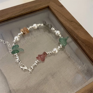 Close-up of natural stone and pearl bracelet with silver lobster clasp on linen