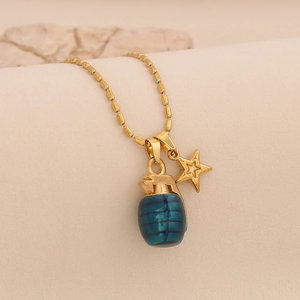 Detail shot of a golden grenade pendant with green resin and a gold star charm