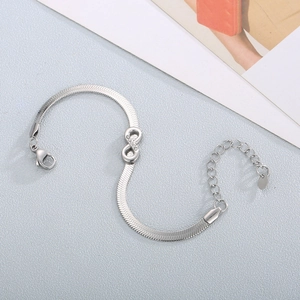 Macro detail of silver infinity symbol on a herringbone blade chain with lobster clasp