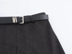 Detail of dark grey wool skirt waist featuring a slim black leather belt with silver buckle