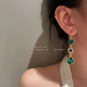 Vintage emerald green teardrop earrings with gold flower accents worn by a model