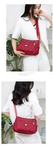 Detail view of burgundy quilted nylon multi-pocket shoulder bag on female model