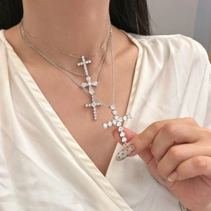 Detail shot of layered silver necklaces with sparkling cross pendants on a model neck