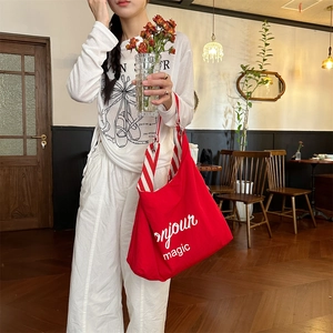 Détail du sac cabas rouge en toile avec imprimé Bonjour et bandoulière rayée