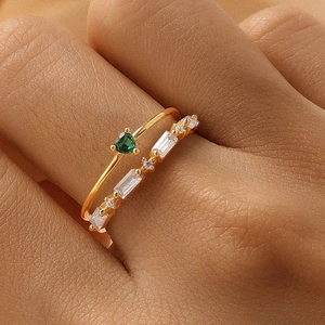 Macro detail of a double-layered gold ring with green heart stone and white zircon stones