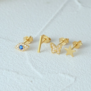 Macro detail of gold S925 silver stud earrings set featuring evil eye and star designs