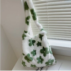 Detail showing plush white tote bag texture with green floral pattern and soft strap