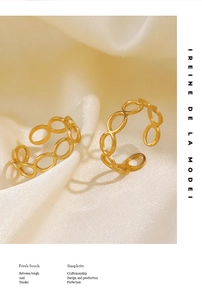 Detail of gold hollow oval chain rings on silk, minimalist titanium steel jewelry