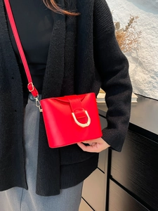 Vintage red bucket bag with gold horseshoe buckle worn with a black knit sweater