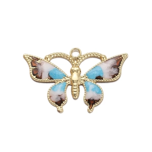 Detailed macro view of a gold butterfly charm with blue and brown enamel for DIY jewelry