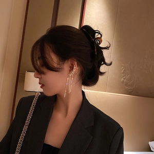 Detail of elegant gold tassel ear cuff with sparkling zircon leaf and long dangling chains