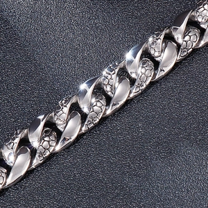 Macro shot of silver stainless steel chain with snake scale texture on black leather