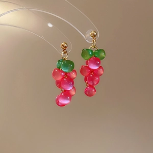 Detailed macro view of pink resin grape drop earrings with green beads on gold studs