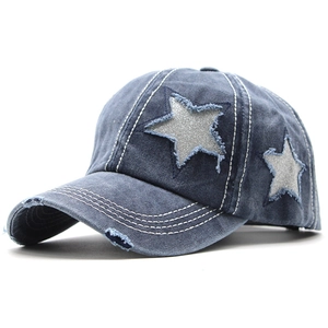 Détail de la casquette en denim bleu délavé avec étoile scintillante et bords effilochés