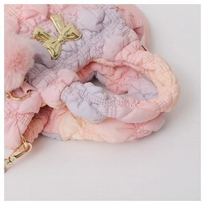 Close-up of pink-purple gradient quilted bag with gold bow and woven handle detail
