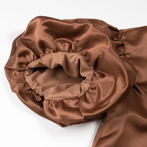Detailed view of elastic cuffs on brown satin puff sleeve blouse with silky texture
