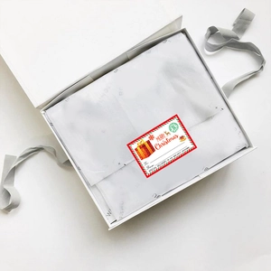 Detail of a white gift box with Merry Christmas sticker, ribbon, and lining paper