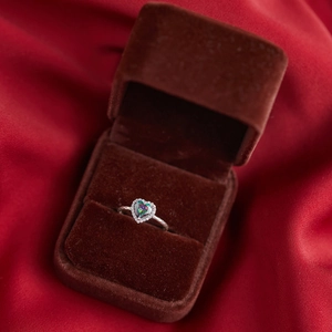 Macro shot of iridescent heart-shaped ring with diamond halo in brown velvet box