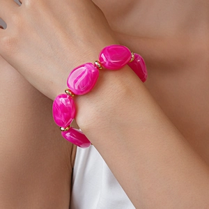 Detail of pink acrylic chunky irregular oval beads with gold spacers on woman's wrist