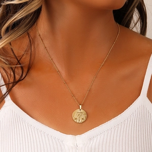 Close-up of a gold stainless steel necklace featuring a Libra zodiac coin pendant