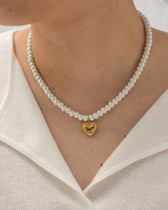 Detailed close-up of a pearl necklace with a vintage golden heart pendant for women