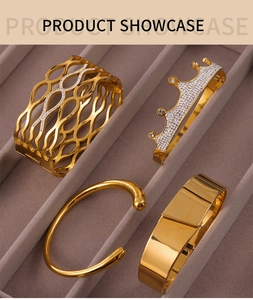 Close-up of four gold bangles with crown, hollow, and minimalist designs on velvet