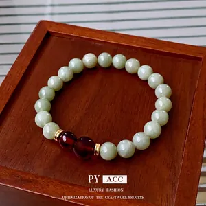Elegant Hetian jade bead bracelet with red garnet accents and gold spacers on wood
