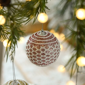 Close-up of pink glitter Christmas ball with white mesh on green pine branches
