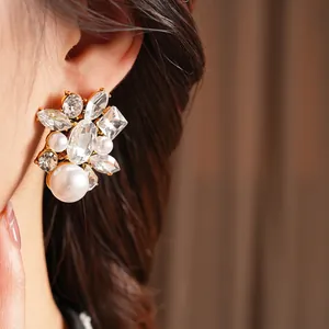 Elegant vintage drop earrings with white pearls and sparkling crystals on gold metal